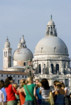 Tourists standing on the Molo San Marco with the Baroque Church of Santa Maria della Salute  by Baldassare Longhena  beyond