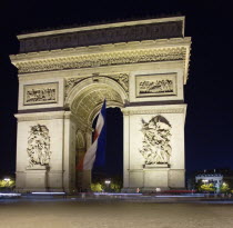 The Arc de Triomphe in Place Charles de gaulle illuminated at night. A large French Tricolour flag hangs from the central archEuropean Nite Western Europe