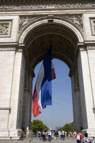 Tourists at the base of the Arc de Triomphe in Place Charles de Gaulle. A large French Triclour flag hangs in the central archEuropean Western Europe