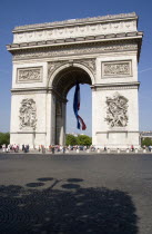 Tourists at the base of the Arc de Triomphe in Place Charles de Gaulle. A large French Triclour flag hangs in the central arch of the ArcEuropean Western Europe