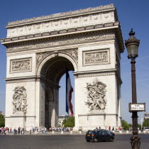 Tourists at the base of the Arc de Triomphe in Place Charles de Gaulle. A large French Triclour flag hangs in the central arch of the ArcEuropean Western Europe