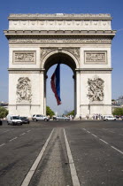 Road traffic on the Champs Elysees leading to the Arc de Triomphe in Place Charles de Gaulle. A large French Triclour flag hangs in the central arch of the ArcEuropean Western Europe