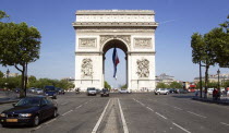 Road traffic on the Champs Elysees leading to the Arc de Triomphe in Place Charles de Gaulle. A large French Triclour flag hangs in the central arch of the ArcEuropean Western Europe