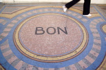 Pedestrian walk across a mosaic on the pavement with the word Bon at the centreCenter European French Western Europe
