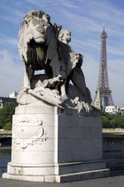 Sculpture of a lion with a child on the Pont Alexandre III bridge with the Eiffel Tower in the distanceEuropean French Western Europe