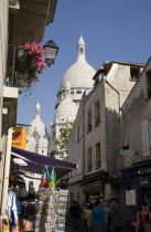 Montmartre The Church of Sacre Couer seen at the end of a narrow street filled with tourists and tourist shops selling souvenirsEuropean French Religion Western Europe