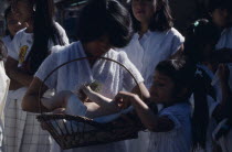 Girls dressed in white and carrying lifesize infant figure during pilgrimage to church.
