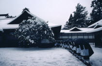 Mount Koya-san.  Venerated Shingon-Buddhist site.  Line of monks wearing black and white robes returning to monastery in thick snow.