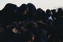 Line of Tuareg women and children wearing typical robes dyed dark indigo.