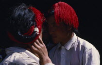 Head and shoulders shot of two Khampa men with hair worn in long braids intertwined with red string.Asian  Asian