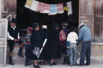 Customers in mix of traditional and westernised dress outside shopfront. American Kids South America Hispanic Latin America Latino American Kids South America Hispanic Latin America Latino