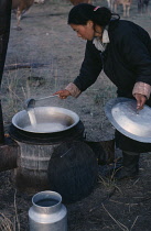 Young woman heating milk.Asia Asian Mongol Uls Mongolian