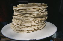 Stack of tortillas on white plate.