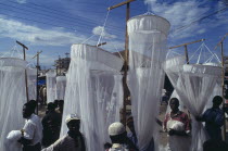 Mosquito nets for sale at market with men in the foreground and seen through the nets.African Eastern Africa Tanzanian  African Eastern Africa Tanzanian