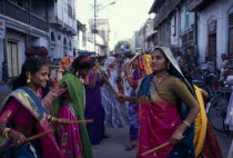 Hindu wedding with women doing a traditional dance with sticks in the street