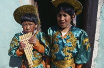 Two boys in costume blowing pipe