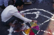 Man painting wheel-like design on the ground to be used as a base for a bonfire during the Holi Festival.Asia Asian Bharat Inde Indian Intiya Religion Religious Asia Asian Bharat Inde Indian Intiya...