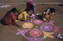 Pongal Festival.  Four day festival to mark the end of harvest.  Women painting decorative floral pattern on ground using coloured powder dyes.Asia Asian Bharat Colored Inde Indian Intiya Religion Re...