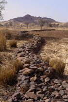 Bund  low rock walls built to prevent soil erosion by flash floods. Stones are placed along the contours on gentle slopes. Sometimes the bunds are reinforced by planting tough grasses along the lines....