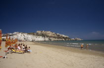 Vieste.  Line of sunbathers on stretch of sandy beach overlooked by castle and apartments on white cliffs beyond.Beaches European Italia Italian Resort Seaside Shore Southern Europe Tourism Tourists...