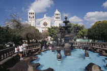 Temple del Senor de Juayua and Plaza.  Children beside fountain in foreground with white exterior facade of the Church of the Cristo Negro or Black Christ behind.American Kids Religion Religious Imma...