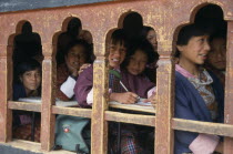 School children in class writing at desks framed in line of low set  arched  glassless windows.Asia Asian Bhutanese Druk Yul Kids Learning Lessons Teaching Immature