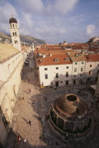 Elevated view over cobbled square with circular stone building in centre  white painted houses with red tiled rooftops  people and bell tower on left.Adriatic Sea Center Croatian European Hrvatska So...
