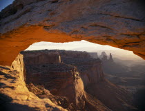 View looking through the Mesa Arch across eroded sandstone cliffs.American North America Scenic United States of America