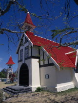 Marie-Reine Church.  White painted exterior with red tiled roof and free standing bell tower  part framed by tree branches.Indian Ocean African Eastern Africa Maurice Mauritian Religion Religious