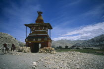 Old  painted stupa marking entrance to Tsarang with two horsemen approaching.chorten Asia Asian Nepalese Religion Religious Scenic 2