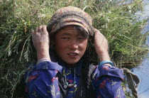 Portrait of young girl carrying load of harvested grasses supported by strap around her forehead.Asia Asian Nepalese Immature One individual Solo Lone Solitary