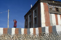 Tibetan Buddhist monk looking out from monastery terrace  shielding his eyes from the sun.Asia Asian Nepalese Religion Religion Religious Buddhism Buddhists One individual Solo Lone Solitary