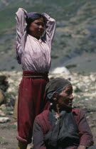 Tibetan nomads.  Elderly seated woman with young girl standing behind with arms raised behind head  both looking away to right.Asia Asian Nepalese  extended family Female Women Girl Lady Kids Old Sen...