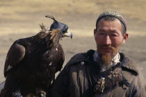Head and shoulders portrait of Kazakh nomad man with golden eagle wearing hood and jesses.hunting bird of prey falconry Asia Asian Bonnet Mongol Uls Mongolian Male Men Guy Male Man Guy One individual...