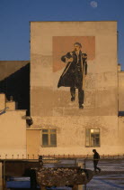 Wall painting depicting Lenin on building in Hovd sum centre with passing figure in middle foreground.Asia Asian Center Mongol Uls Mongolian One individual Solo Lone Solitary