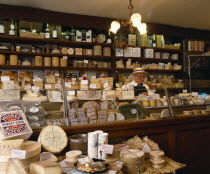 Man behind counter of specialist cheese delicatessenMale Men Guy Male Man Guy One individual Solo Lone Solitary