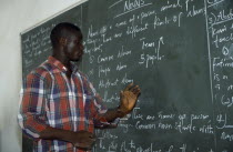 English teacher standing beside blackboard giving grammar lesson.African Learning Lessons Nigerian Teaching Western Africa