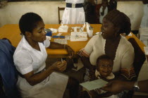 UNICEF vaccination project.  Female nurse with woman and crying child.Innoculation  injection African Children Female Women Girl Lady Kids Nigerian Western Africa Female Woman Girl Lady