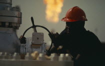 Portrait of oil worker with flare of burnt off gas behind him.African Nigerian Western Africa