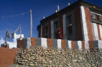 Head monk looking out from terrace of temple painted with coloured stripes.Colored Asia Asian Nepalese Religion Religious