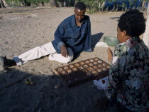 Fishing village with a couple playing an age old game called MbaoAfrican Eastern Africa Tanzanian