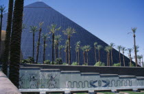 The Luxor Hotel exterior with replica pyramid and hieroglyphics.  Water feature and line of palm trees in the foreground.American North America United States of America