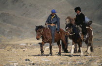 Kazakh men on their way to the Kazakh New Year festivities riding horses and leading pack camel.Asia Asian Equestrian Male Man Guy Mongol Uls Mongolian Male Men Guy