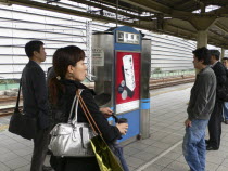 Yurakucho - the smokers spot on the train platform  men and a young woman smokingAsia Asian Japanese Nihon Nippon Female Women Girl Lady Male Man Guy Female Woman Girl Lady Gray Male Men Guy Grey Imm...