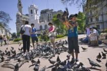 Feeding the pigeons in Plaza de Mayo.HolidaysTourismTravelBuenos AiresSouth AmericaUrbanPlaza de MayoFunBirdsAmerican Argentinian Hispanic Latin America Latino Gray Grey