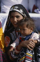 Kalbelia dancer woman holding her baby at the Camel FestivalAsia Asian Nepalese Bharat Inde Indian Intiya Male Men Guy Male Man Guy Babies Female Women Girl Lady Kids Religion Female Woman Girl Lady...