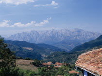 View towards the Picos de Europa mountains in northern Spain from the Posada la Trebede  Perrozo. Tiled rooftops of village and the Val de Liebana valley.Peaks from right to left: Torre de Cerrodo  P...