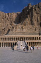 Deir el-Bahri. Hatshepsut Mortuary Temple. Visitors walking towards ramped entrance with limestone cliffs behind.African Middle East North Africa History Religion Religious