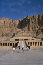 Deir el-Bahri. Hatshepsut Mortuary Temple. Visitors walking towards ramped entrance with limestone cliffs behind.African Middle East North Africa History Religion Religious