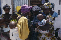 Women and children queuing outside rural clinic.African Gambian Kids Western Africa Female Woman Girl Lady Female Women Girl Lady